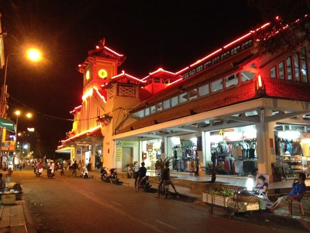 Các gian hàng trước mặt chợ với quần áo, trái cây và đồ ăn nhanh