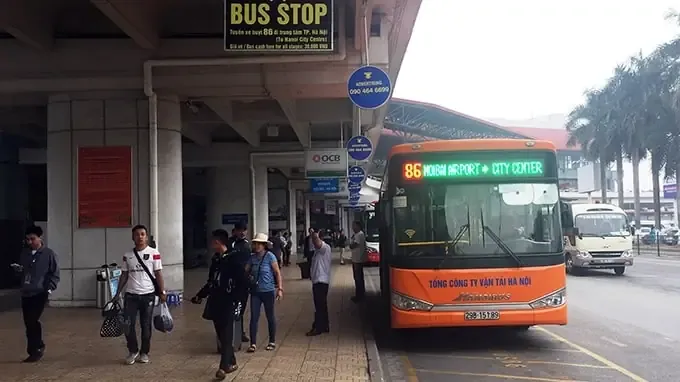 Hành khách xem lịch trình xe buýt trên bảng điện tử tại bến